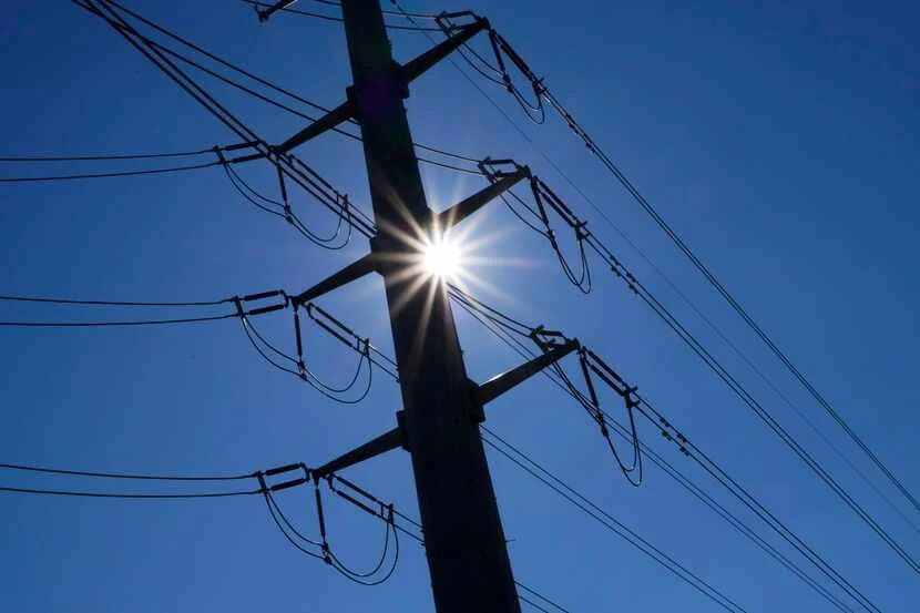 Power pole and lines silhouetted against the sun