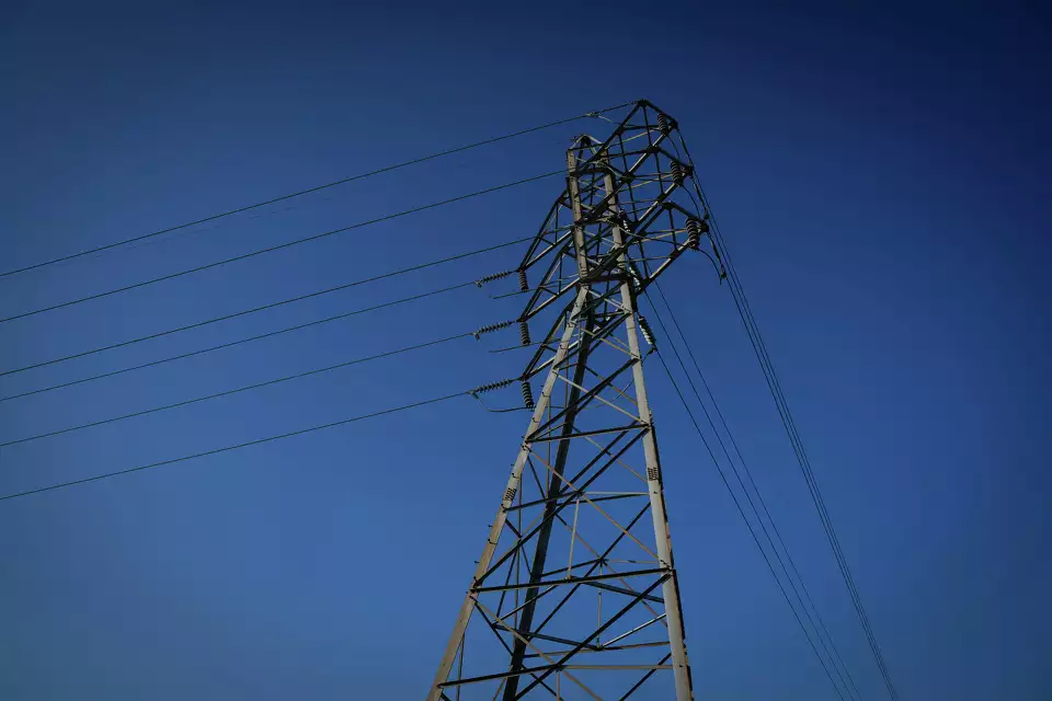 Steel transmission tower against a deep blue sky